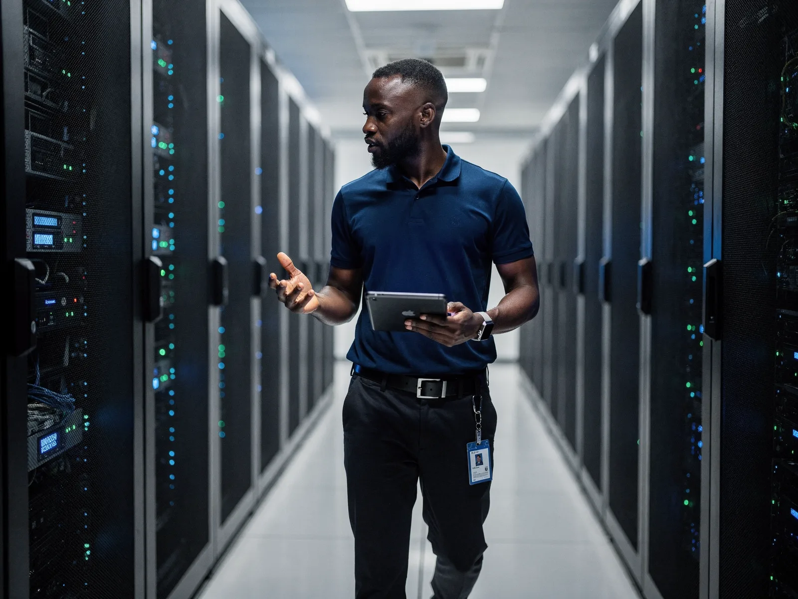 Technician walking through a row of illuminated server racks in a modern data centre