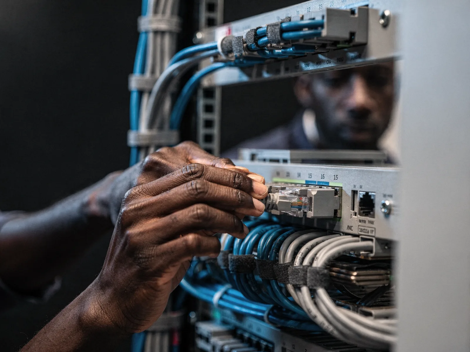 Technician patching structured cabling into a network switch and patch panel